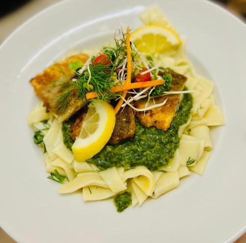 a plate of pasta with lemon slices and vegetables at Traditionsgasthaus Goldener Löwe Riesa Restaurant & Pension in Riesa