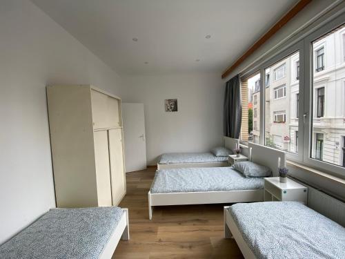 Cette chambre comprend 3 lits et une fenêtre. dans l'établissement St Thomas House, à Anvers