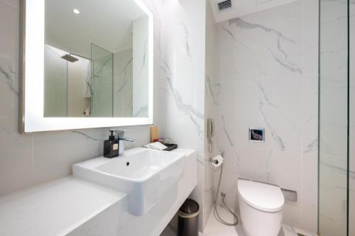 a white bathroom with a sink and a toilet at Grand Richmond Stylish Convention Hotel in Nonthaburi