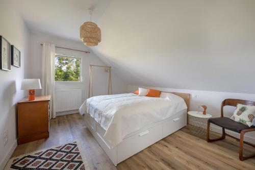 ein weißes Schlafzimmer mit einem Bett und einem Stuhl in der Unterkunft Calme, detente et modernite a Sarzeau in Sarzeau