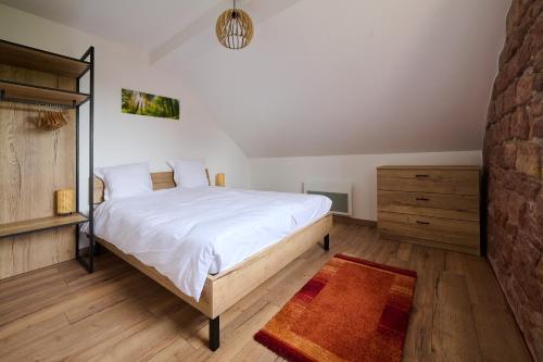 a bedroom with a large white bed and a wooden floor at Le Noyer - Appt avec terrasse et jardin partagé in Puberg