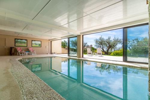 - une piscine intérieure dans une maison dotée de portes en verre dans l'établissement Le Mas des Moulières - Vue montagne avec piscine, à Tourrettes-sur-Loup