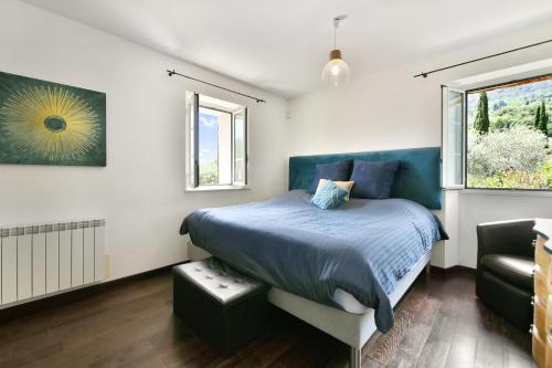 een slaapkamer met een blauw bed en een raam bij Lou Mas Nachiano - Charmante maison avec piscine in Spéracèdes