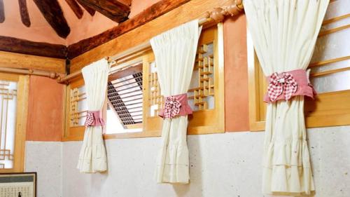 two windows with white curtains in a room at Beautiful Garden Fine Day House in Jeonju