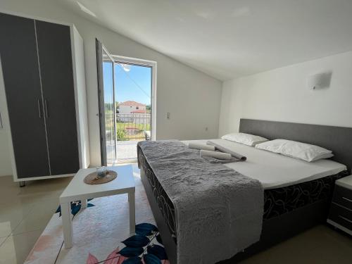 1 dormitorio con cama, mesa y ventana en MB Apartments, en Ulcinj