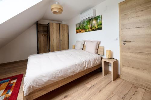 een slaapkamer met een wit bed en een houten vloer bij Le Pommier - Appt avec jardin partagé in Puberg