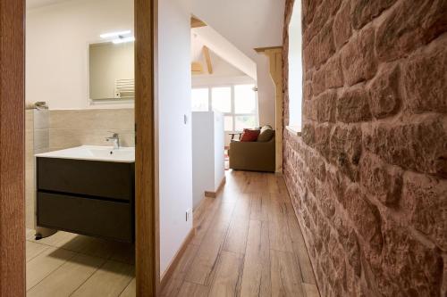 a bathroom with a sink and a stone wall at Le Pommier - Appt avec jardin partagé in Puberg