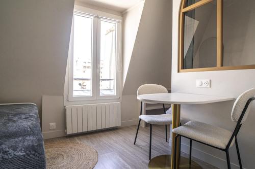 Zimmer mit einem Tisch, Stühlen und einem Fenster in der Unterkunft Bright 20m near the Eiffel Tower in Paris