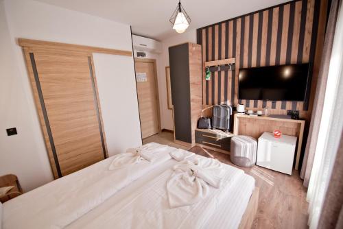 a bedroom with a large white bed and a flat screen tv at СПА Хотел Романтика in Sarnitsa