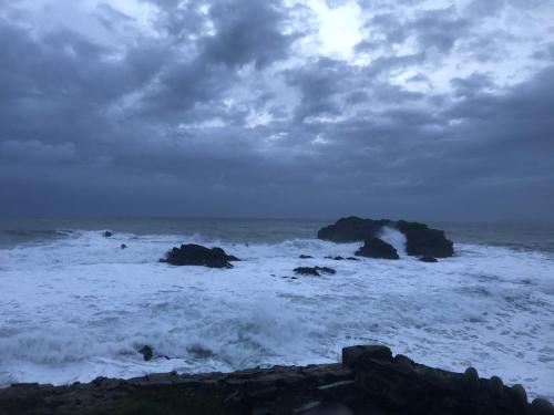 a beach with some waves and rocks in the ocean at Unfurnished Bell Tent close to SWC path in Hartland