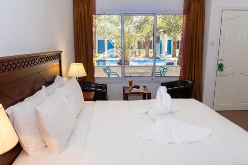 Schlafzimmer mit einem Bett mit weißer Bettwäsche und einem Fenster in der Unterkunft Fujairah Hotel & Resort in Fudschaira