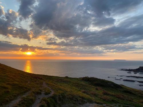a sunset over the ocean with the sun setting at Unfurnished Bell Tent close to SWC path in Hartland