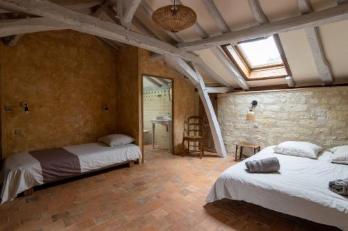 1 dormitorio con 2 camas y pared de piedra en Gîte Divin - Belle maison champêtre, en Doué-la-Fontaine