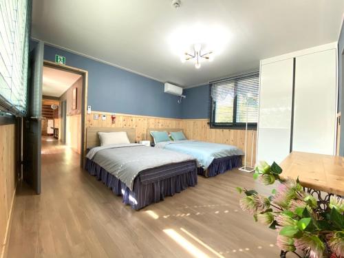 2 łóżka w pokoju z niebieskimi ścianami w obiekcie Sodamhyang Pension w mieście Czedżu