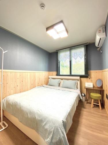 a bedroom with a large bed and a window at Sodamhyang Pension in Jeju