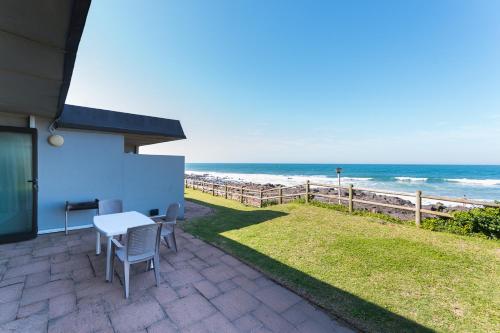 a patio with a table and chairs and the beach at Boulder Bay 9 in Ballito