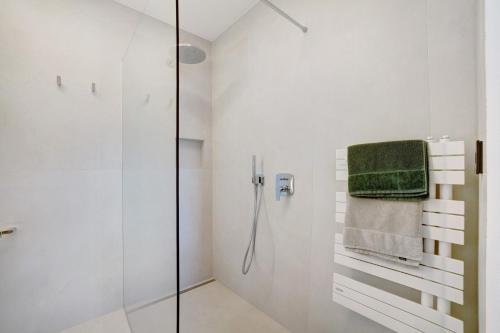 uma casa de banho branca com uma cabina de duche em vidro e toalhas verdes em Alivo Living Apartment Olivia em Rifiano