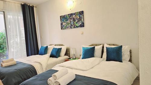 two beds in a room with blue and white pillows at Villa Alba Apartments in Dobra Voda