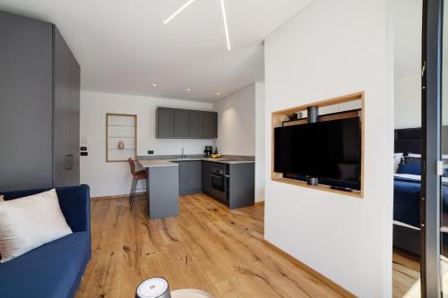 a living room with a blue couch and a kitchen at Alivo Living Apartment Aurora in Rifiano
