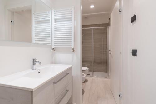 a white bathroom with a sink and a toilet at Palazzetto La Quadra di San Faustino - F&L Apartment in Brescia