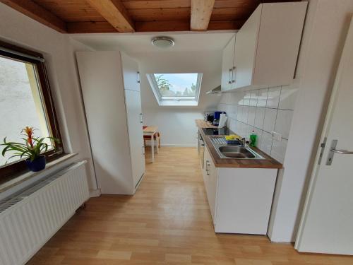 a kitchen with white cabinets and a wooden floor at Gemütliche zentrale DG Wohnung in Mühlacker in Mühlacker