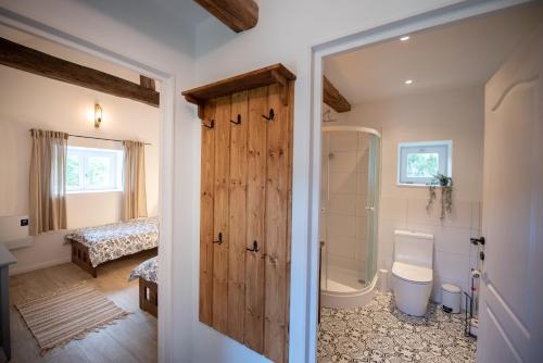 baño con ducha, aseo y puerta en Florie Cottage en Cserszegtomaj