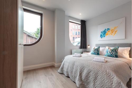 a bedroom with a bed with blue pillows and a window at Apartment Thirty Six Staines Upon Thames - Free Parking - Heathrow - Thorpe Park in Staines