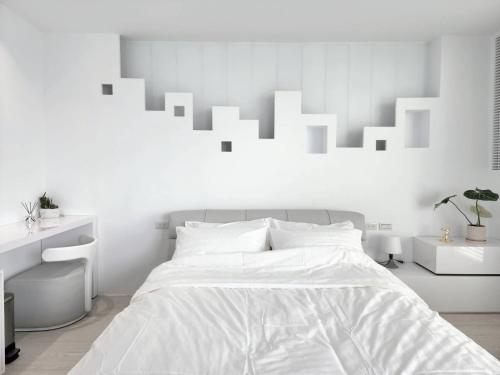 a white bedroom with a bed with white walls at White window sea in Hengchun