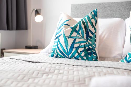 a white bed with blue and white pillows on it at Apartment Thirty Six Staines Upon Thames - Free Parking - Heathrow - Thorpe Park in Staines