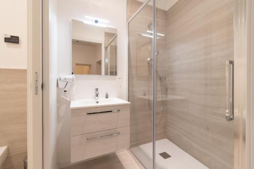 uma casa de banho com um chuveiro, um lavatório e um espelho. em Palazzetto La Quadra di San Faustino - F&L Apartment em Brescia