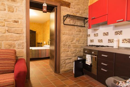 a kitchen with red cabinets and a room with a bed at B&B La casa di Giulietta in Castelmezzano