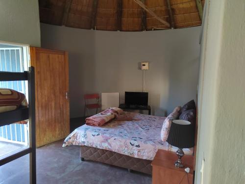 1 dormitorio con 1 cama y 1 mesa con lámpara en Graskop family retreat and backpackers, en Graskop