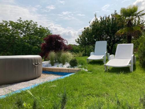 two white chairs sitting in the grass near a pool at Cascina Bramasole in Celle Enomondo
