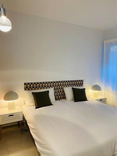 une chambre avec un grand lit blanc avec deux lampes dans l'établissement Le Viagio Superbe appartement avec jacuzzi, à Sarlat-la-Canéda