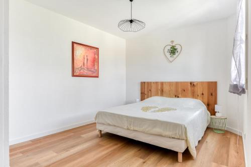 a white bedroom with a bed and a wooden floor at La Villa d'Isa et Seb in Narbonne