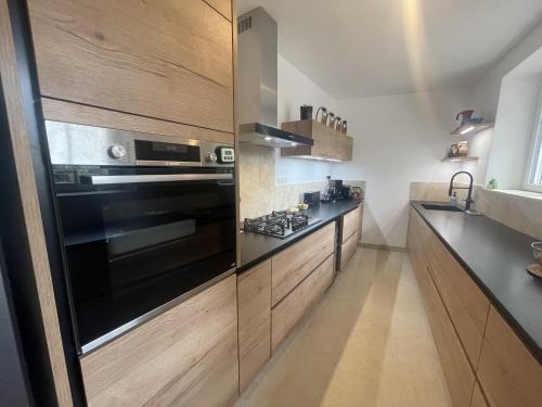 La cuisine est équipée d'un four noir et de placards en bois. dans l'établissement Le Tilleul des Cloux - Au Coeur de Auxey-Duresses, à Auxey-Duresses