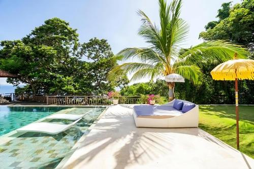 a pool with two lounge chairs and an umbrella at Raaga Samudra Villa in Padangbai
