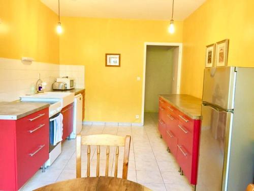 une cuisine avec des armoires rouges et jaunes et une table dans l'établissement Cottage du château, à Erbrée