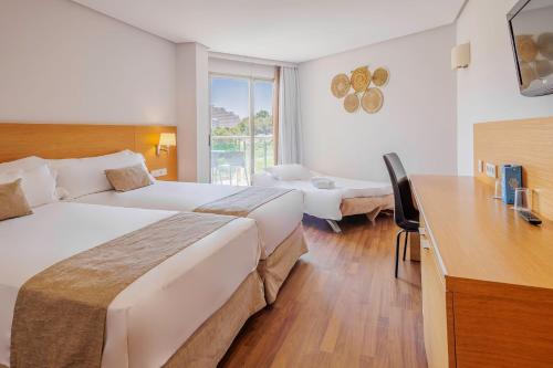 a hotel room with two beds and a desk at Cullera Holiday in Cullera