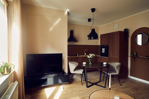 a living room with a table and chairs and a television at Apartament Studio Garnizon in Gdańsk