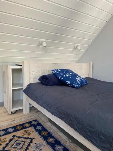 a bed with a blue pillow on top of it at Leniwa Kolonia in Sarnaki