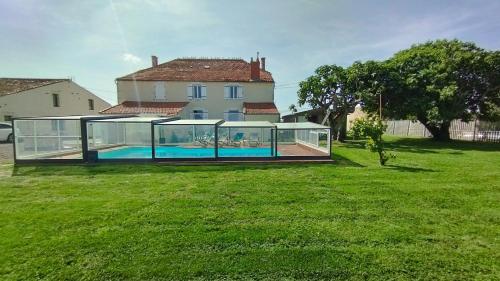 a glass house with a swimming pool in a yard at Le Making Of Chambres d'Hôtes insolites et Familiales in Thairé
