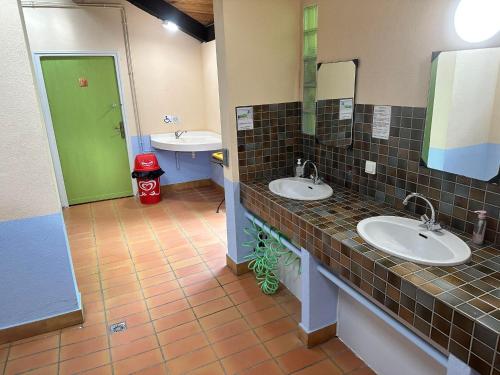 uma casa de banho com dois lavatórios e uma porta verde em LES EYCHECADOUS em Artigat