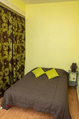 - une chambre avec un lit et 2 oreillers jaunes dans l'établissement Residence du marche, à Jonzac