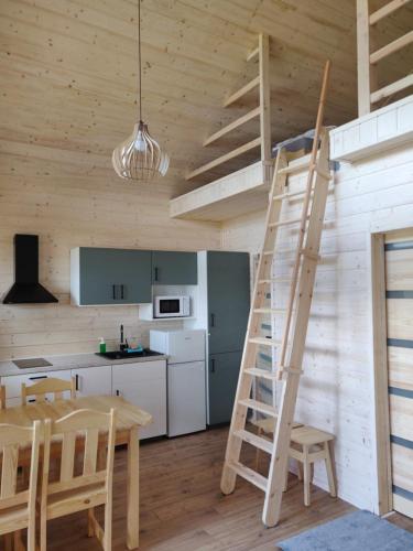 a kitchen with a ladder and a table in a room at Kujanki - domki z widokiem na jezioro in Zakrzewo