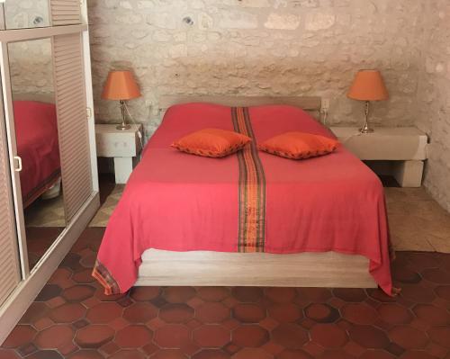 sypialnia z czerwonym łóżkiem i 2 pomarańczowymi poduszkami w obiekcie La Laiterie du Logis w mieście Chaniers