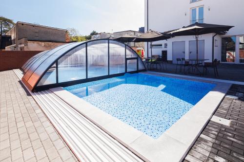 a swimming pool with a glass roof on top of a house at Pod Winogronem - Apartamenty z basenem i wyżywieniem in Pobierowo