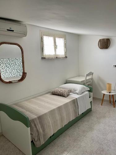 a bedroom with a bed with a mirror and a chair at Villa Patty in Marzamemi