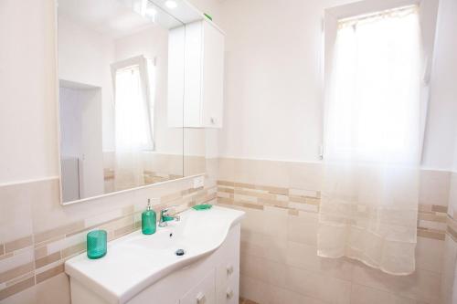 bagno bianco con lavandino e specchio di Villetta Capo Bianco - Goelba a Portoferraio