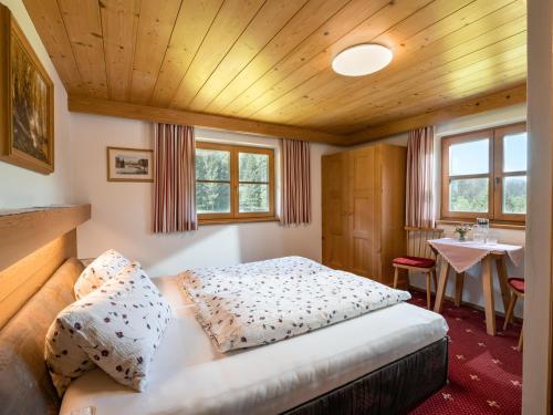 Schlafzimmer mit einem Bett, einem Tisch und Fenstern in der Unterkunft Bauernhof Niederfilzboden in Fieberbrunn